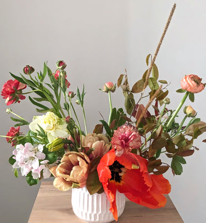 Arrangement of British grown flowers in red, peach and orange in white ceramic container